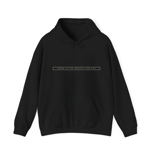 Black hoodie with text "BORN IN THE MUSCLE CAR ERA," featuring an adjustable hood and kangaroo pocket.